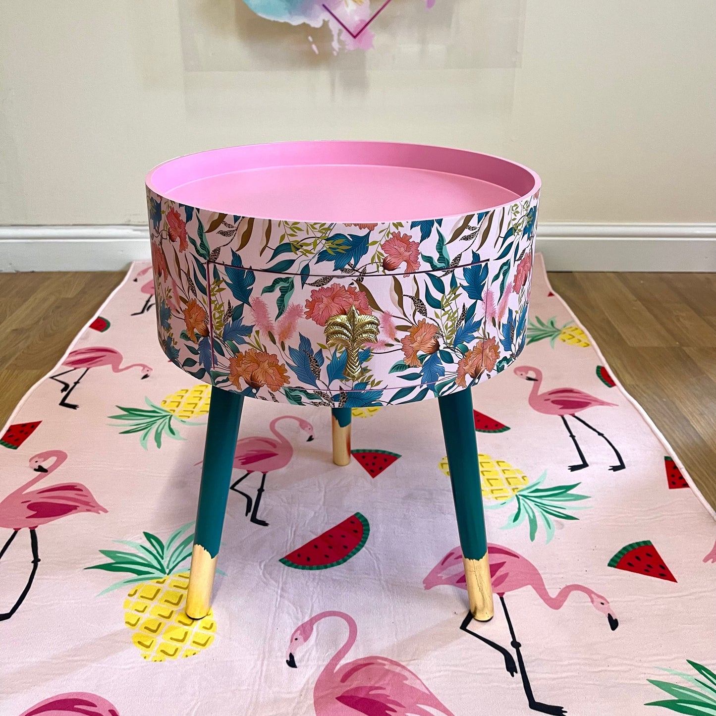 Floral - pink and green wooden round side table with leaf and flower design. Inbuilt drawer and three legs with gold painted palm tree handle