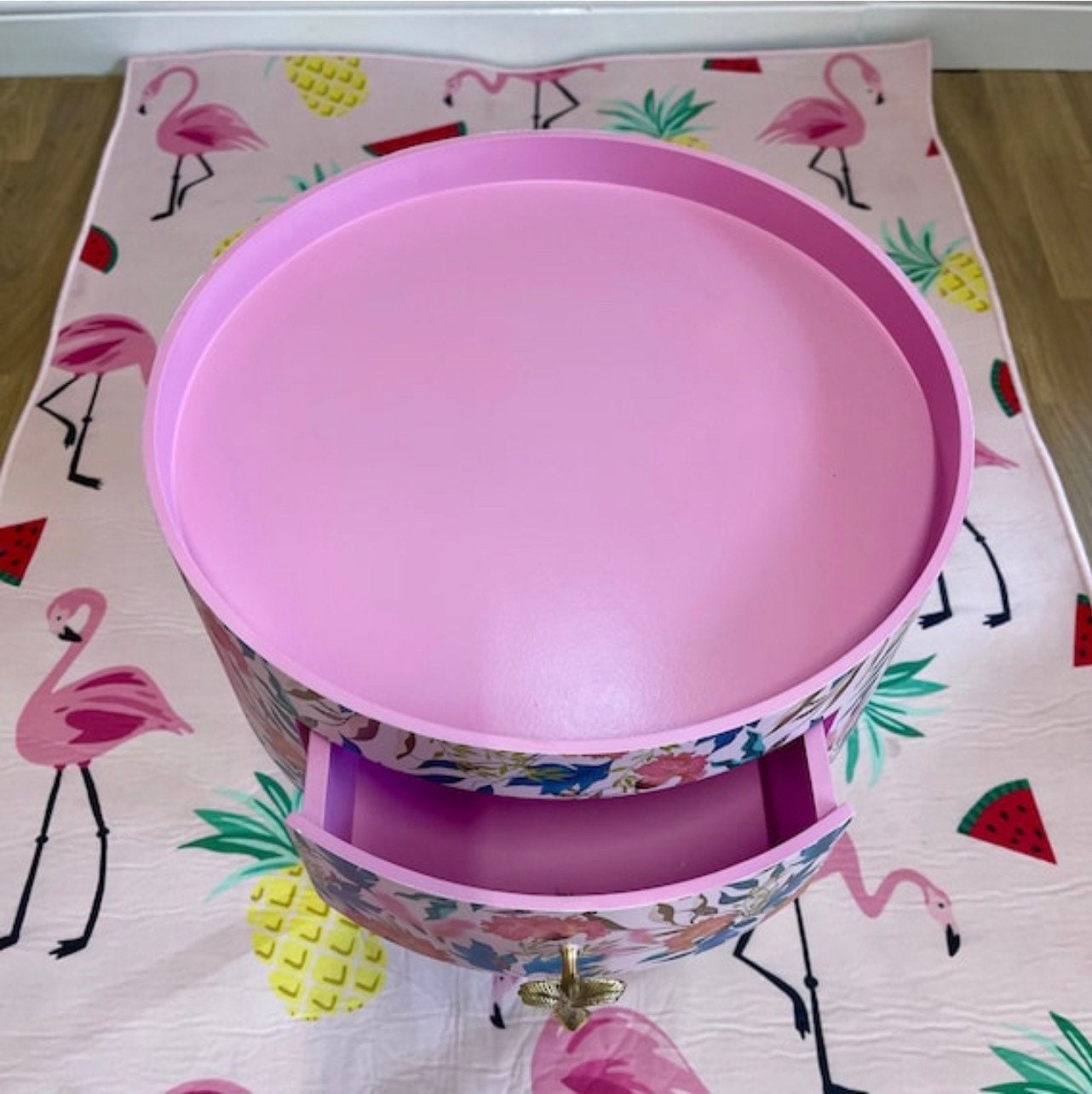 Floral - pink and green wooden round side table with leaf and flower design. Inbuilt drawer and three legs with gold painted palm tree handle