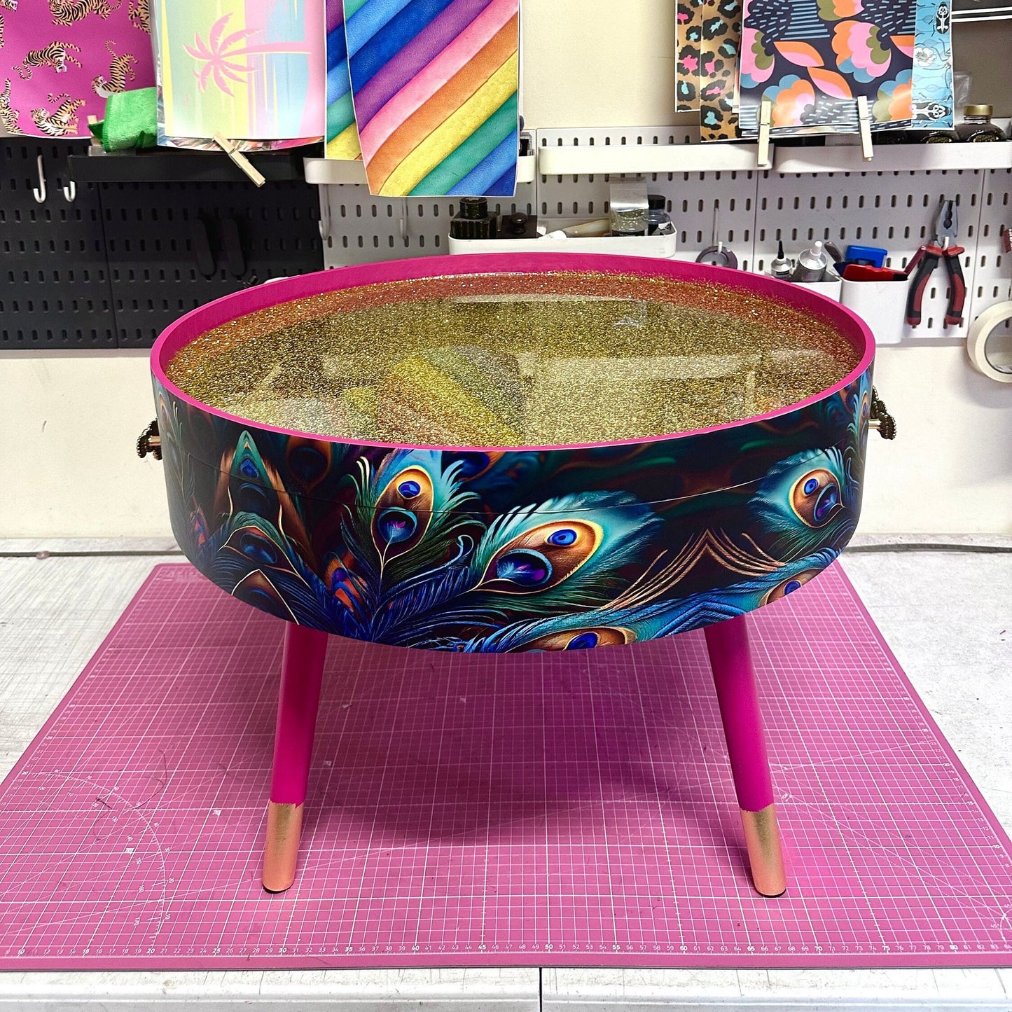 Round coffee table , peacock design, blue, teal and turquoise feathers. Bright pink. Round table, lift off top for storage. End table lounge