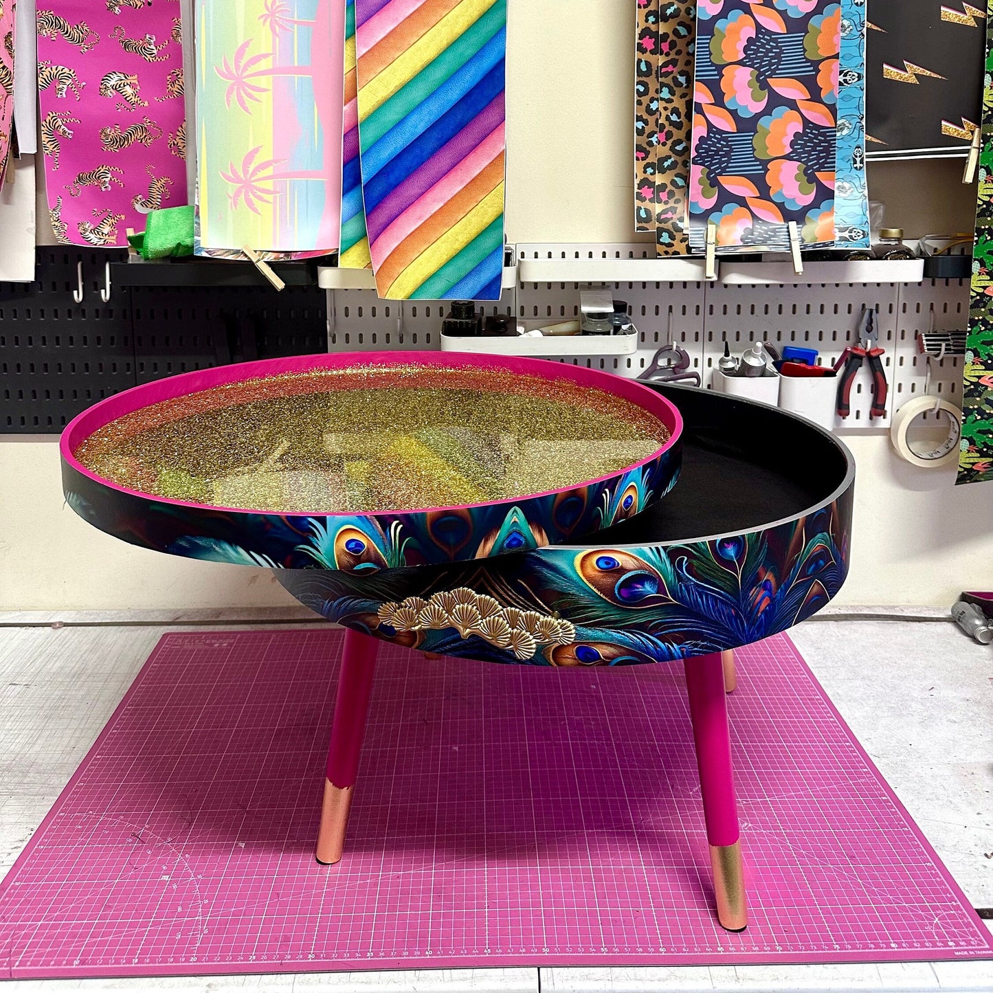 Round coffee table , peacock design, blue, teal and turquoise feathers. Bright pink. Round table, lift off top for storage. End table lounge