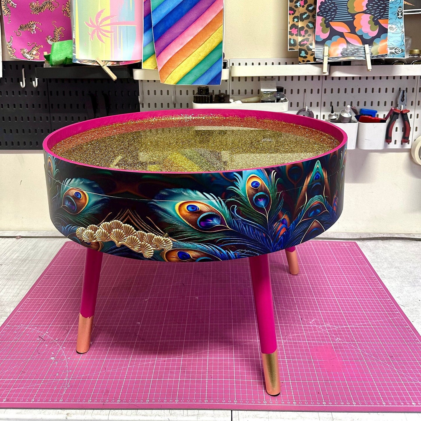 Round coffee table , peacock design, blue, teal and turquoise feathers. Bright pink. Round table, lift off top for storage. End table lounge