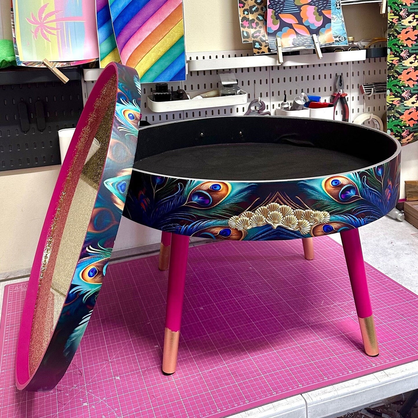 Round coffee table , peacock design, blue, teal and turquoise feathers. Bright pink. Round table, lift off top for storage. End table lounge