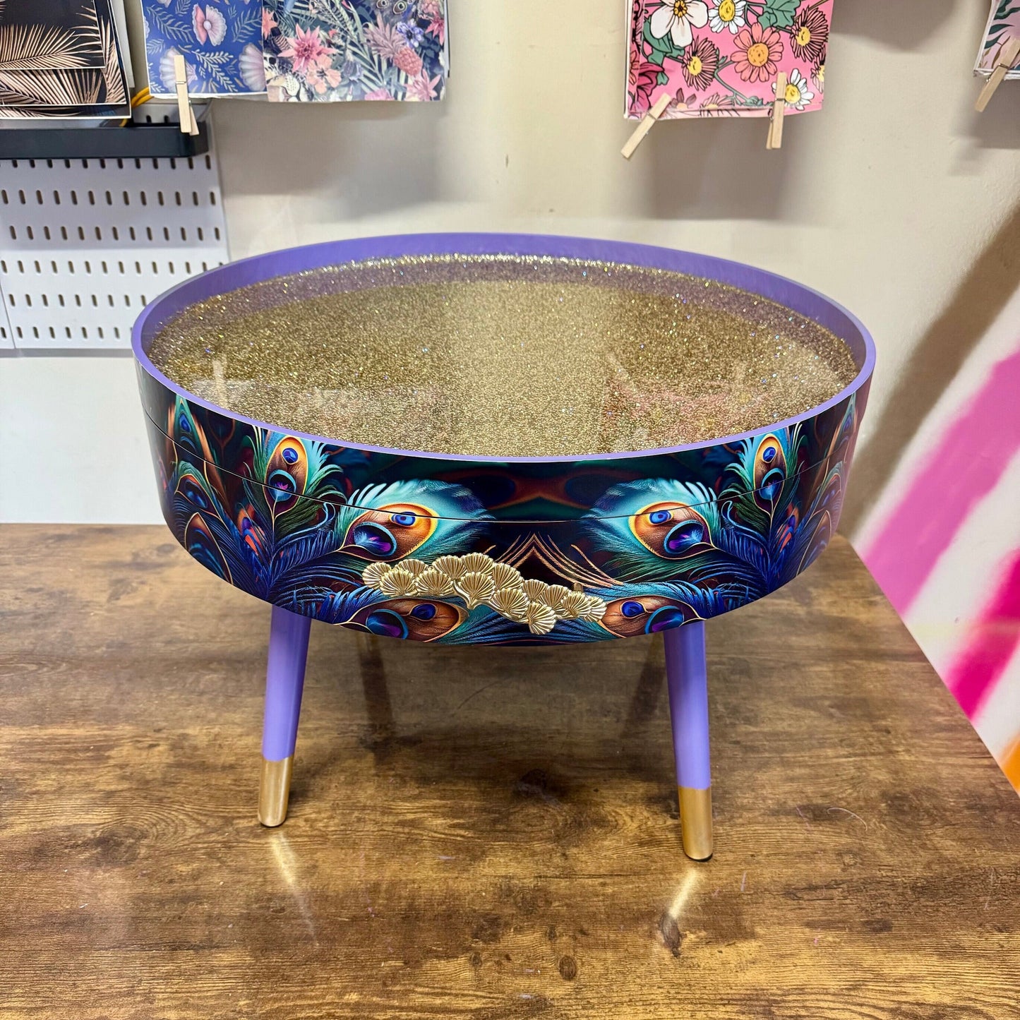 Round coffee table , peacock, blue, teal and turquoise feathers. Lilac purple gold glitter . Round table, storage, End table lounge