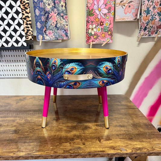 Round coffee table , peacock design, blue, teal and turquoise feathers. Bright pink and gold, lift off top for storage. End table lounge