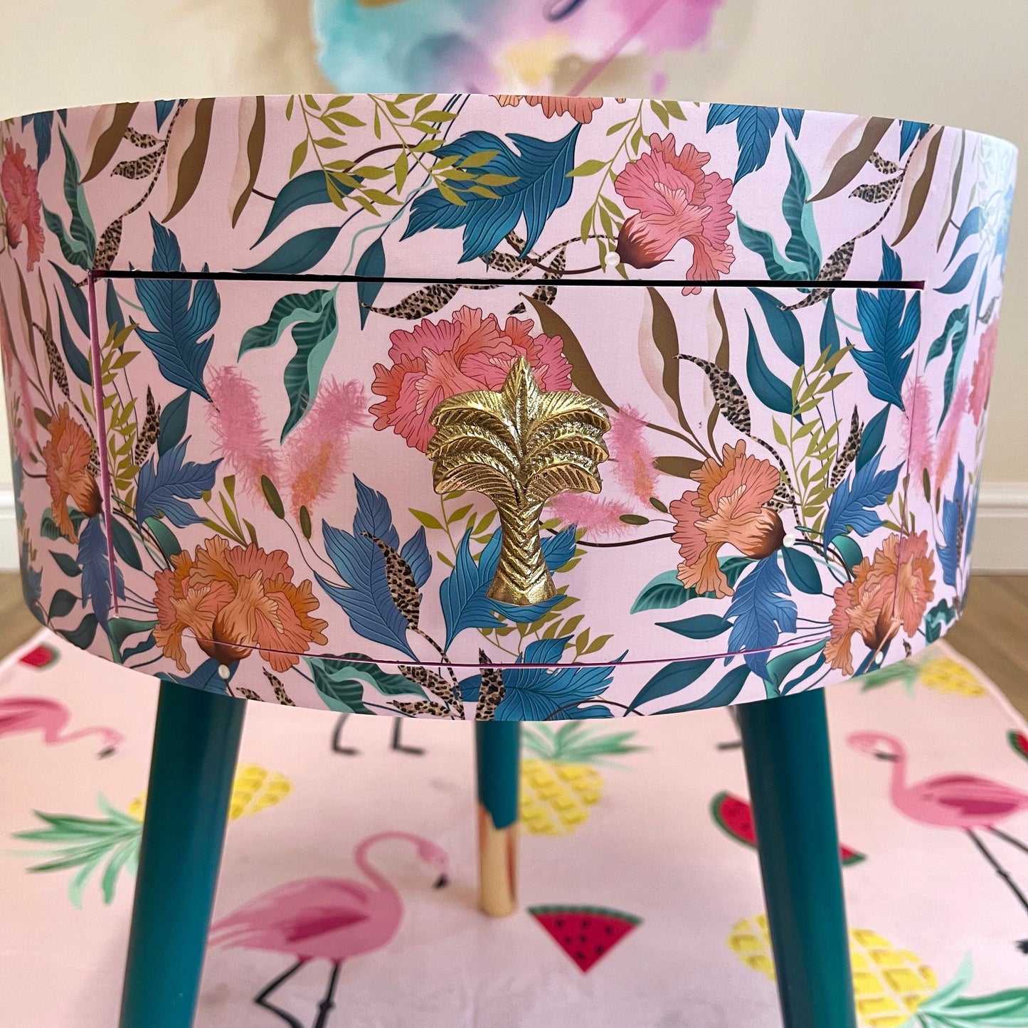 Floral - pink and green wooden round side table with leaf and flower design. Inbuilt drawer and three legs with gold painted palm tree handle