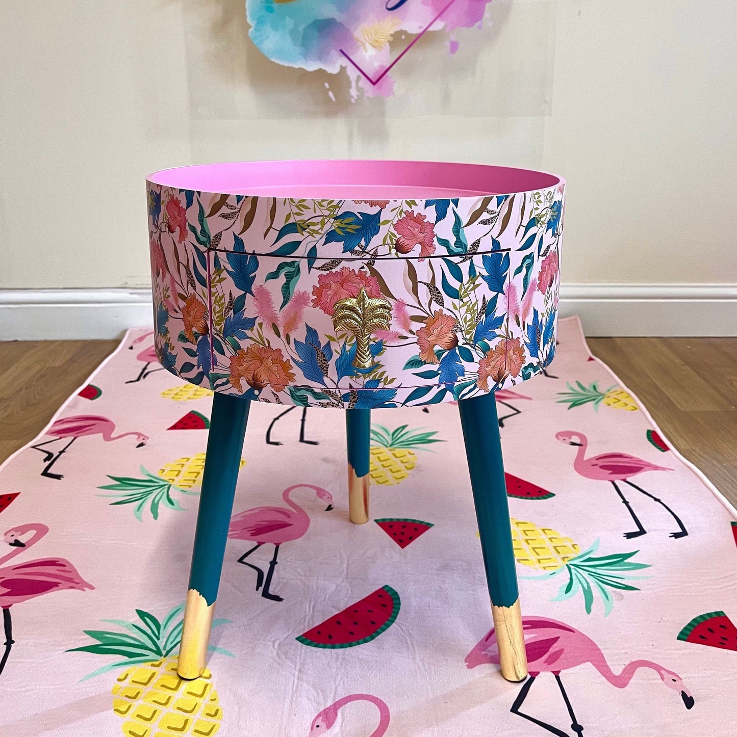 Floral - pink and green wooden round side table with leaf and flower design. Inbuilt drawer and three legs with gold painted palm tree handle
