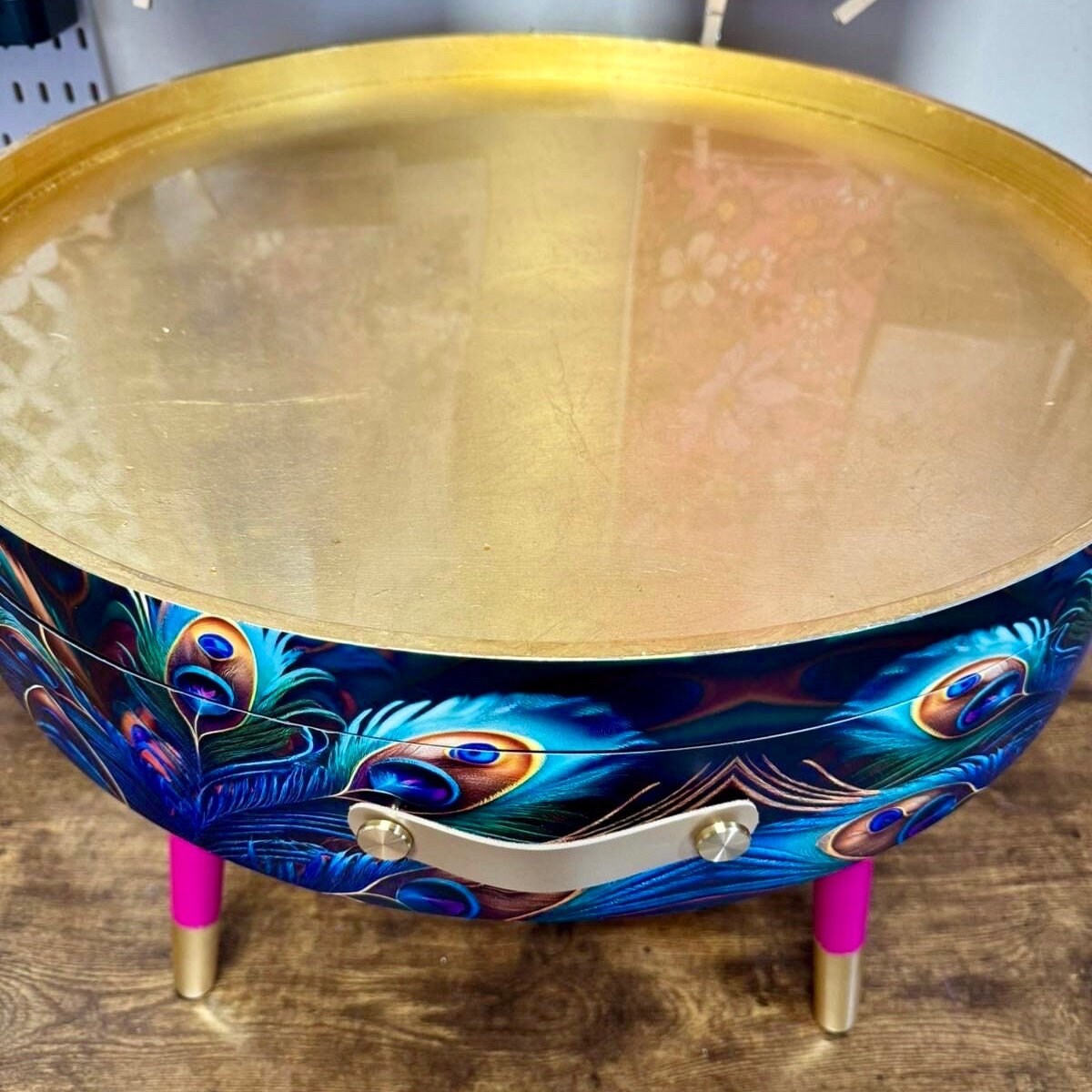 Round coffee table , peacock design, blue, teal and turquoise feathers. Bright pink and gold, lift off top for storage. End table lounge
