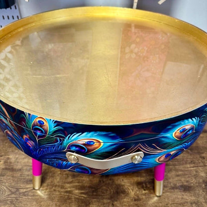 Round coffee table , peacock design, blue, teal and turquoise feathers. Bright pink and gold, lift off top for storage. End table lounge